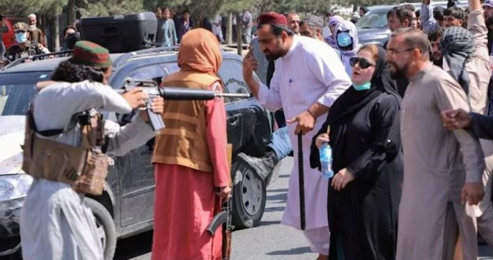 Indescriptible foto de mujer afgana parada frente a un arma talibán