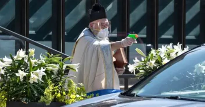 Sacerdote respeta la sana distancia y da bendiciones con pistola de agua