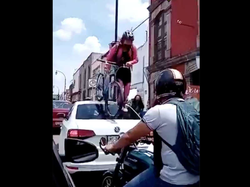 Una joven pasa con todo y bici por encima de auto que no respetó la ciclovía